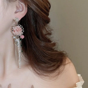 Close-up of pink flower tassel earrings worn by a model in soft lighting