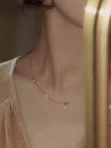 Elegant gold necklace with sparkling clover charms worn by model for luxury display