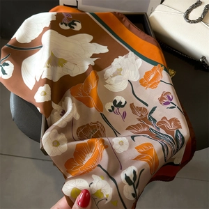 Gros plan d'un foulard en soie à fleurs aux tons marron et orange avec une texture lisse
