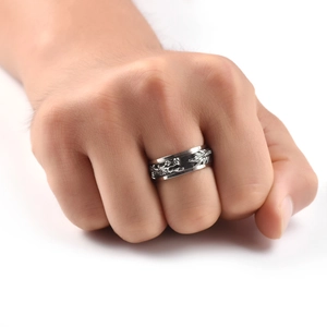 Macro detail of men's stainless steel spinner ring featuring a silver dragon totem pattern