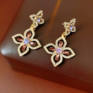 Macro detail of vintage gold floral earrings with purple and pink gemstones in a brown box