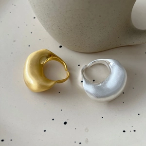 Minimalistische matgouden en zilveren onregelmatige open ringen op een sierbordje