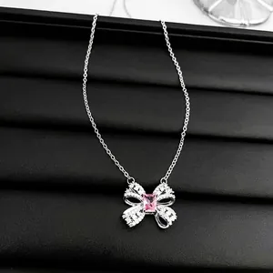 Pink zircon bow heart necklace with silver chain on black leather background