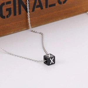 Gros plan d'un pendentif cube noir avec la lettre X sur une chaîne en O argentée