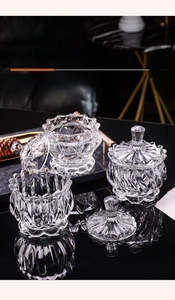 Detailed view of thick textured glass storage jars with lids on black mirror surface