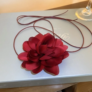 Macro shot of dark red fabric flower with long ribbon on a gift box for versatile styling