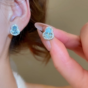 Gros plan d'une boucle d'oreille gourde en zircon bleu clair sur l'oreille