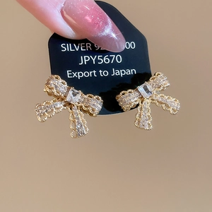 Macro shot of gold-plated silver bow earrings with sparkling cubic zirconia on display