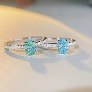 Macro detail of oval cut mint and blue gemstones on silver rings with pavé diamonds