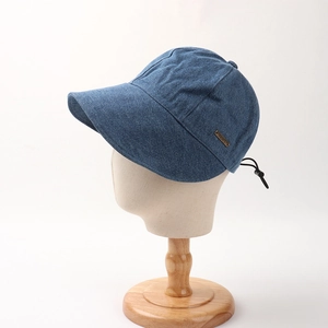 Detail view of denim sun hat with side metal logo plate and adjustable drawstring