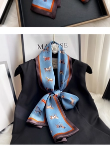 Detailed view of the blue silk scarf featuring an equestrian horse pattern and striped edges