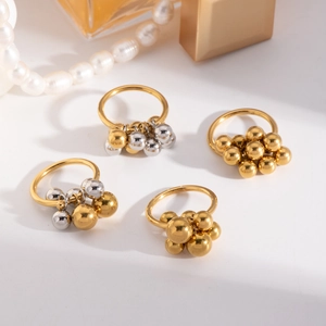 Detail of four vintage gold ball rings arranged with pearls on a clean white background