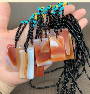 Detailed view of hand-held natural agate pendant with bohemian beaded ethnic necklace