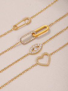 Macro shot of gold-plated necklaces with cubic zirconia charms and heart motifs
