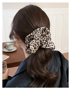 Detailed view of a vintage leopard print scrunchie styled on a model's ponytail