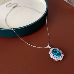 Detailed macro view of an oval blue gemstone flower pendant on a silver luxury chain