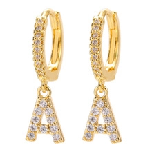 Detail of gold-plated hoop earrings with crystal-encrusted letter A tassel charms