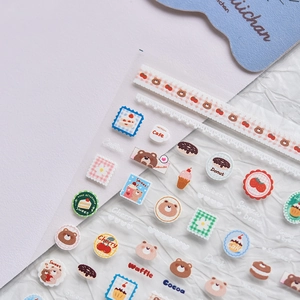 Close-up of cartoon bear and fruit nail stickers with cute hand-drawn patterns