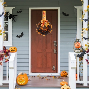 Halloween wreath on front door with pumpkin ribbons, bats and spiders decor
