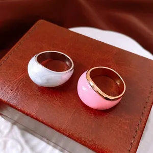Anelli tondi minimalisti in smalto bianco marmo e rosa su un portagioie di lusso raffinato
