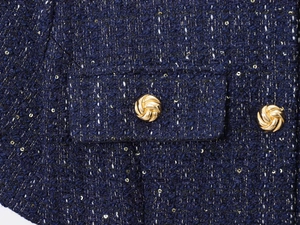 Dettaglio della giacca in tweed blu scuro con paillettes dorate e bottoni in metallo