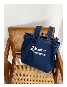 Détail du sac cabas en denim bleu foncé avec imprimé Les Mondays More Sundays sur chaise
