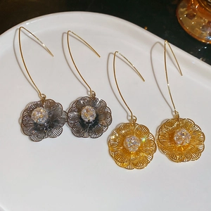 Détail macro de boucles d'oreilles fleur en or 18 carats et métal avec zircons brillants