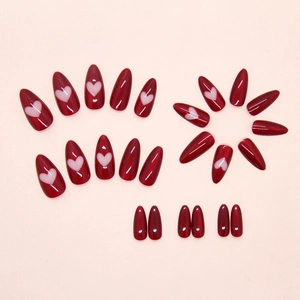 Glossy burgundy almond press-on nails featuring white hollow heart designs on pink background
