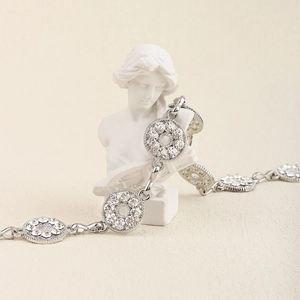 Close-up of a silver rhinestone body chain draped over a white classical bust sculpture