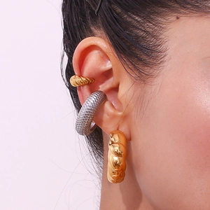 Macro detail of gold twisted rope hoop earrings and silver scale textured ear cuffs