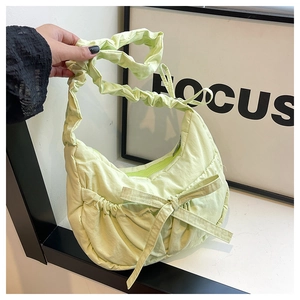 Detail of lime green nylon handbag featuring ruching texture and large bow decoration