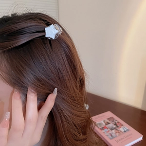 Gros plan d'une barrette étoile blanche nacrée portée sur de longs cheveux bruns