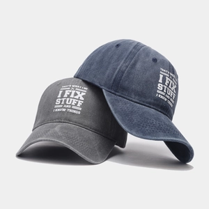 Detail of washed cotton baseball caps in charcoal and navy with printed text slogan