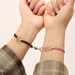 Close-up of magnetic matching dog charms on pink and black waxed cord bracelets