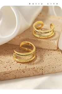 Macro detail of gold layered ear cuffs with colorful zircons and geometric saw texture