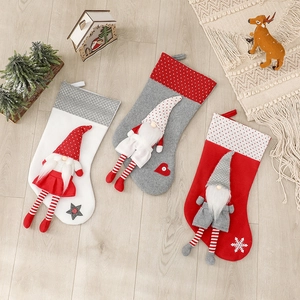 Three Nordic Christmas stockings with gnome dolls on a wooden floor background