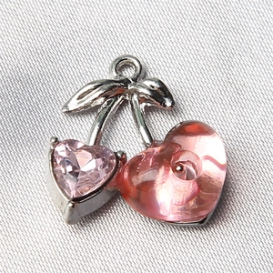 Macro shot of pink heart-shaped cherry charms for jewelry with silver leaves