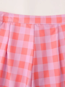 Detailed view of pink and coral plaid fabric with pleated texture and elastic waist