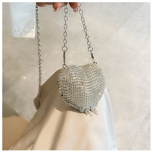 Close-up of heart-shaped mini evening bag with silver rhinestones and metal tassels