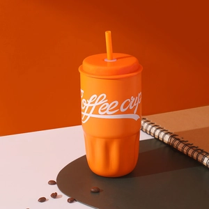 Dettaglio della tazza da caffè arancione con cannuccia, trama ondulata e chicchi di caffè