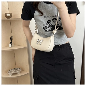 Detail of off-white crescent underarm bag featuring a silver bow metal decoration