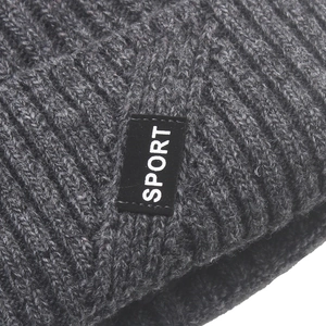 Macro shot of gray knit beanie showing thick texture and black SPORT woven label