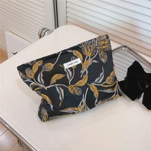Detail der Goldtulpen-Stickerei auf schwarzer Stoff-Kosmetiktasche mit Webeetikett