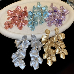 Detail of long pleated petal tassel earrings in five colors on a display tray
