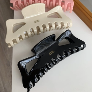 Détail de grandes pinces à cheveux en acétate avec inscription dorée Barrette La France en tons neutres