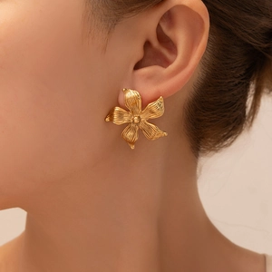 Detail of vintage gold flower stud earrings featuring 3D radial texture on model