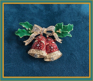 Detailed close-up of Christmas bells brooch with red enamel and gold crystal bow