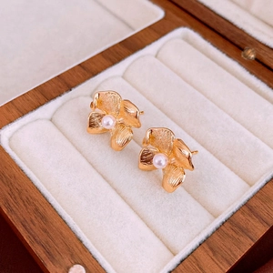 Detailed shot of gold flower pearl earrings in a premium wooden jewelry display box