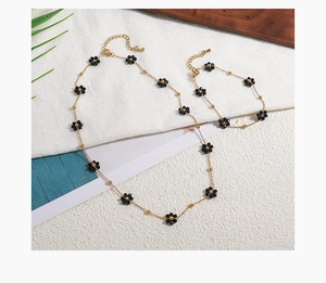 Detailed macro view of 18K gold-plated daisy necklace with natural black stone accents