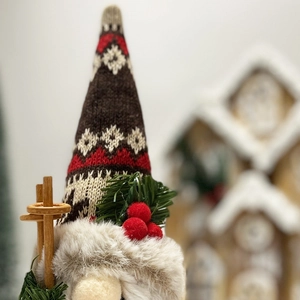 Close-up of Christmas gnome with knitted hat and pine branch details on wooden background